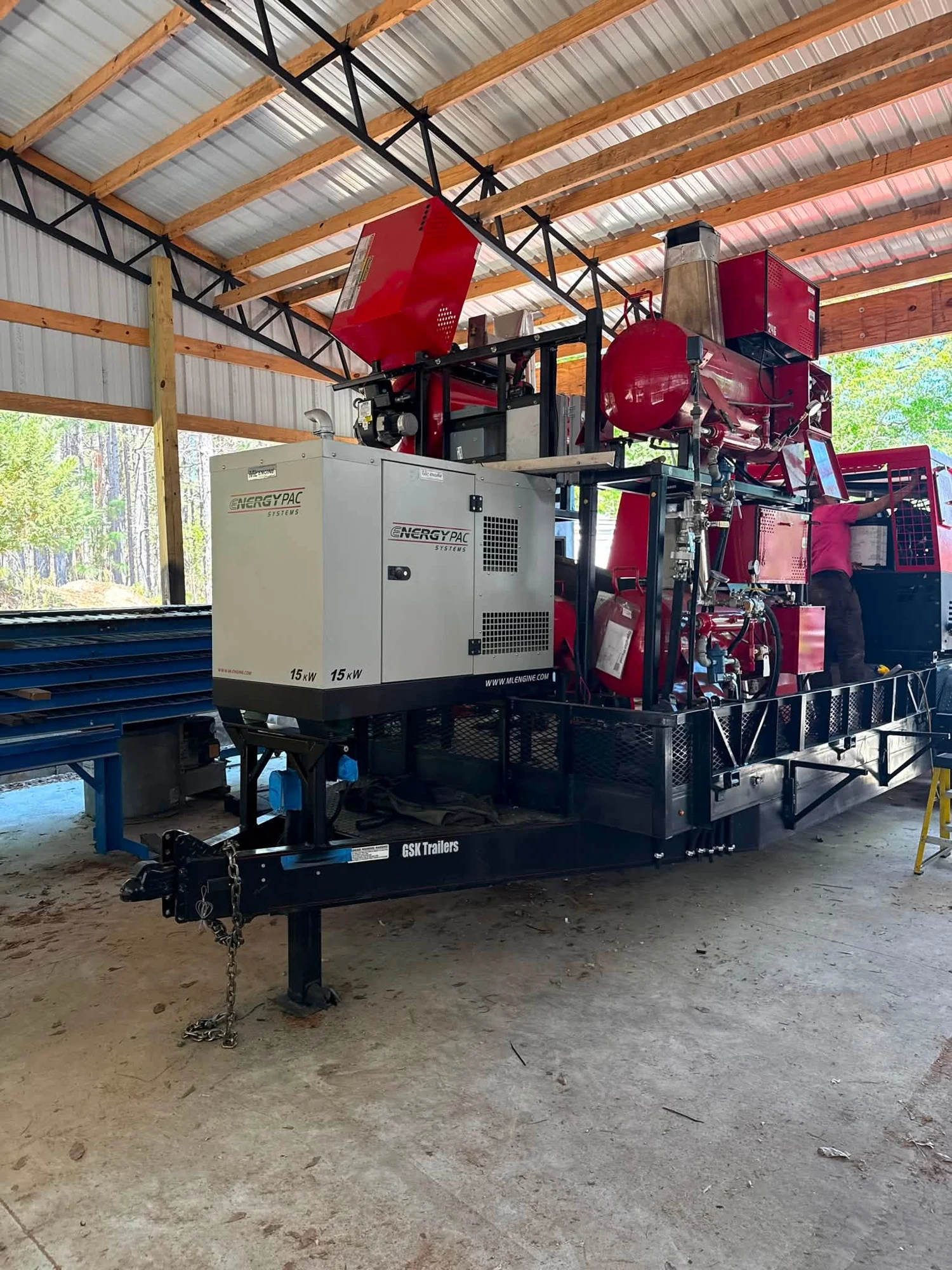 Trailer-mounted equipment and a generator in a covered workshop.